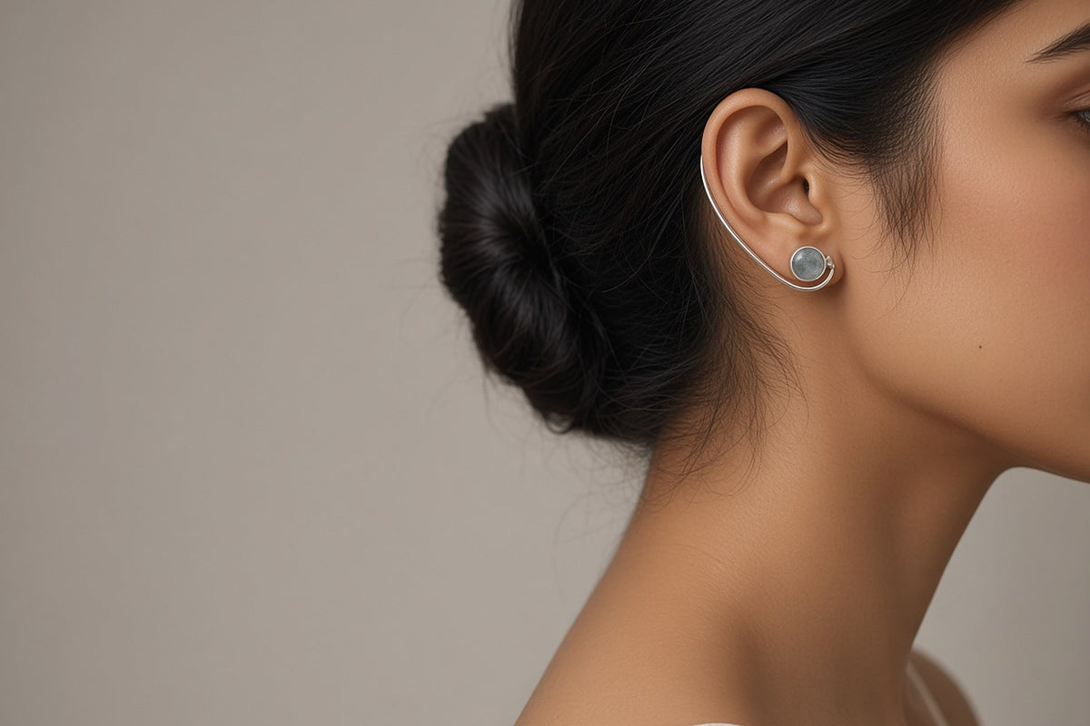 Minimal silver ear cuff with a grey-blue stone worn on the ear, side profile