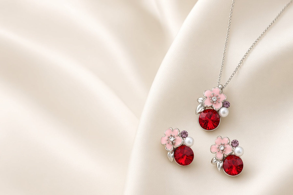 Silver pendant necklace and stud earring set with pink enamel flower, pearl and red crystal on ivory silk