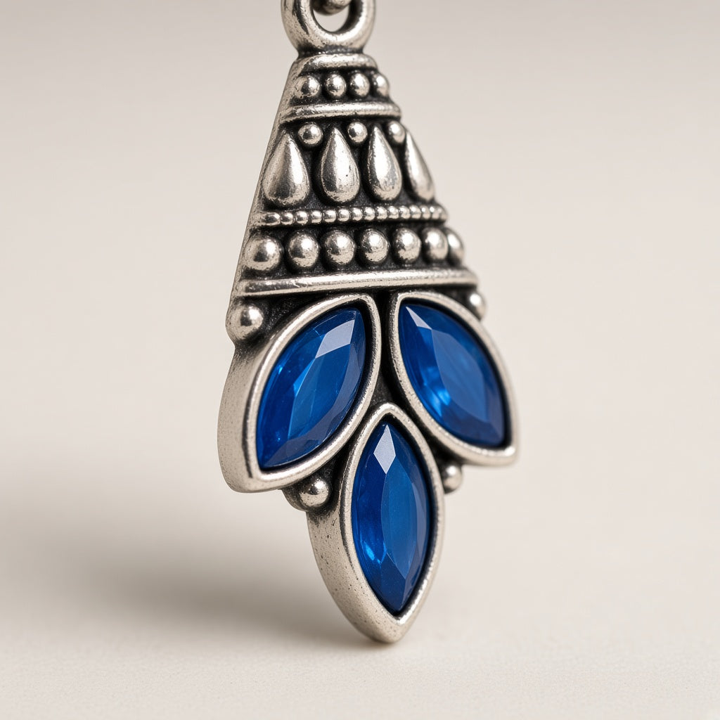 Parna earrings close-up of oxidised crown and blue marquise stones