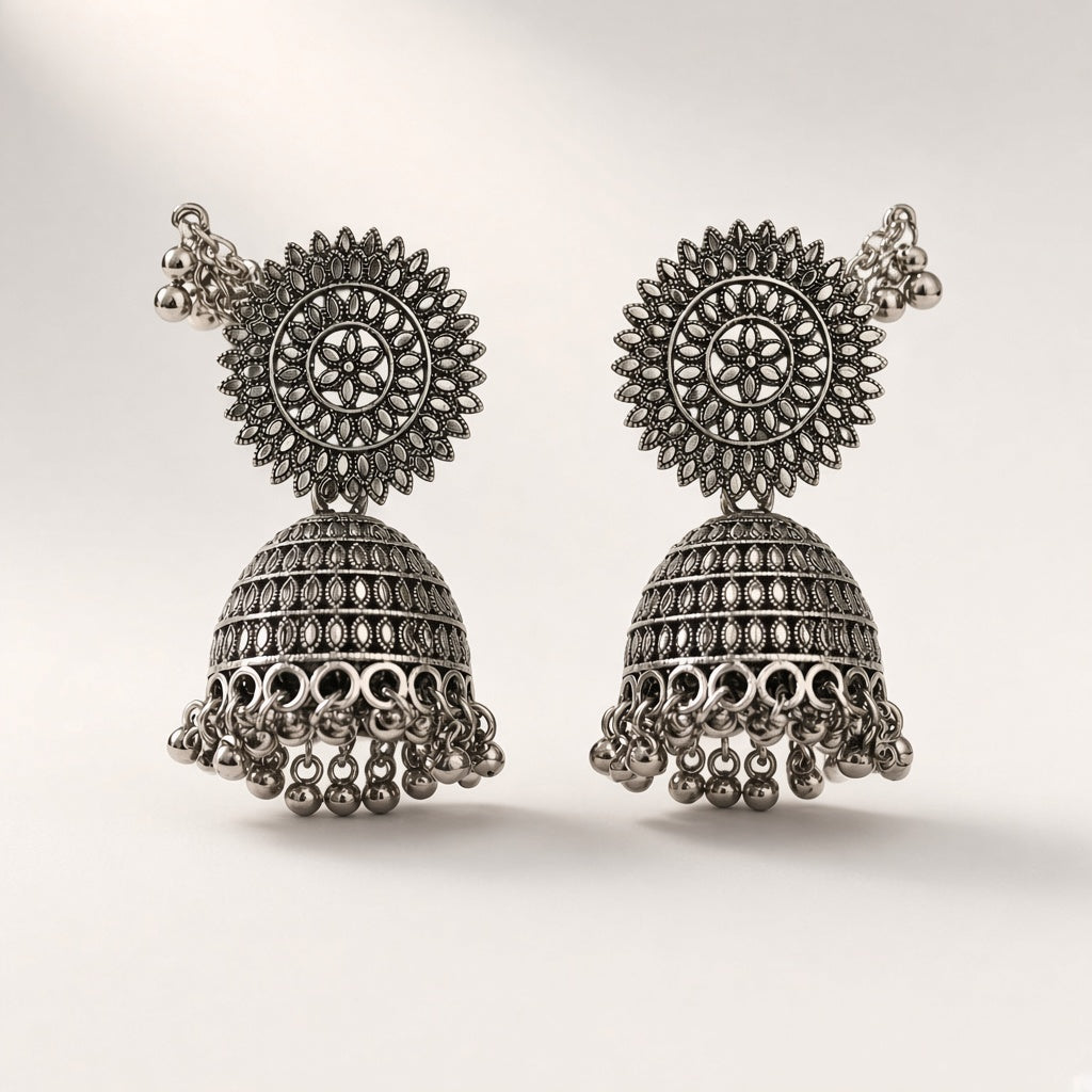 Surya oxidised silver-tone jhumkas with sunburst stud, filigree bell, ghungroo fringe and ear-chain, studio shot